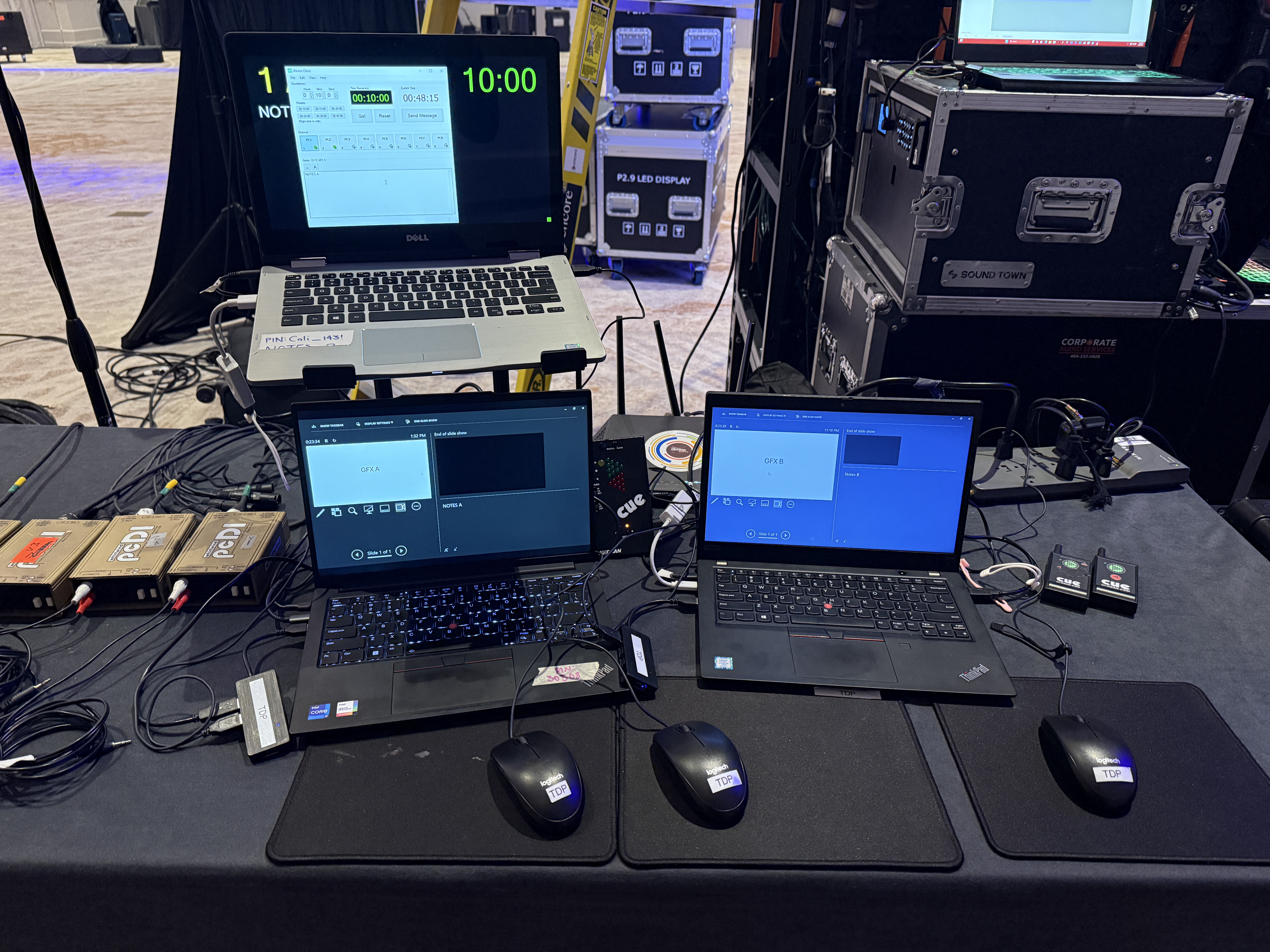 A chaotic live event production desk with multiple laptops and cables